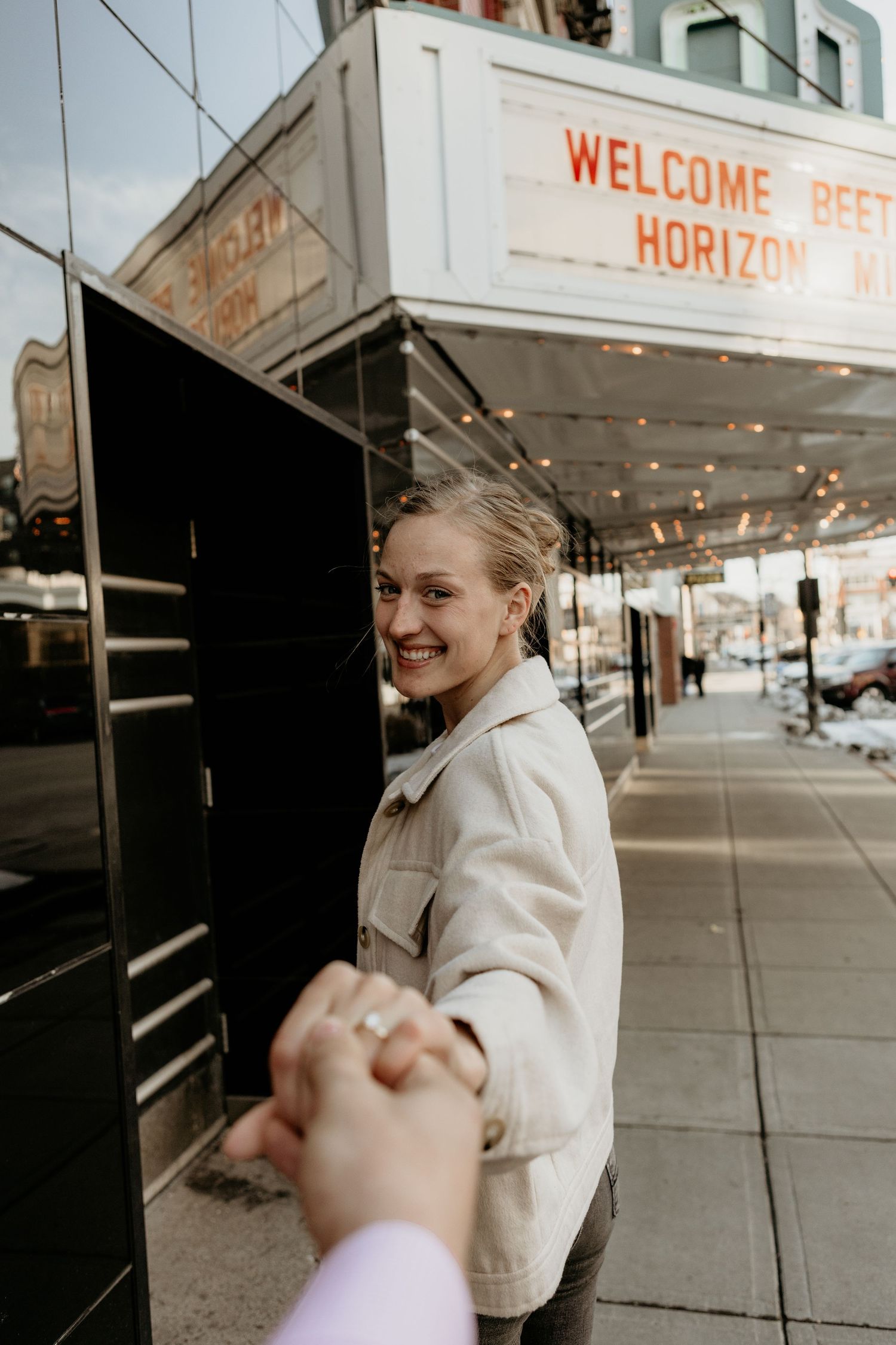 A sequence of photos showing someone in a beige jacket walking along a sidewalk under a welcome sign.