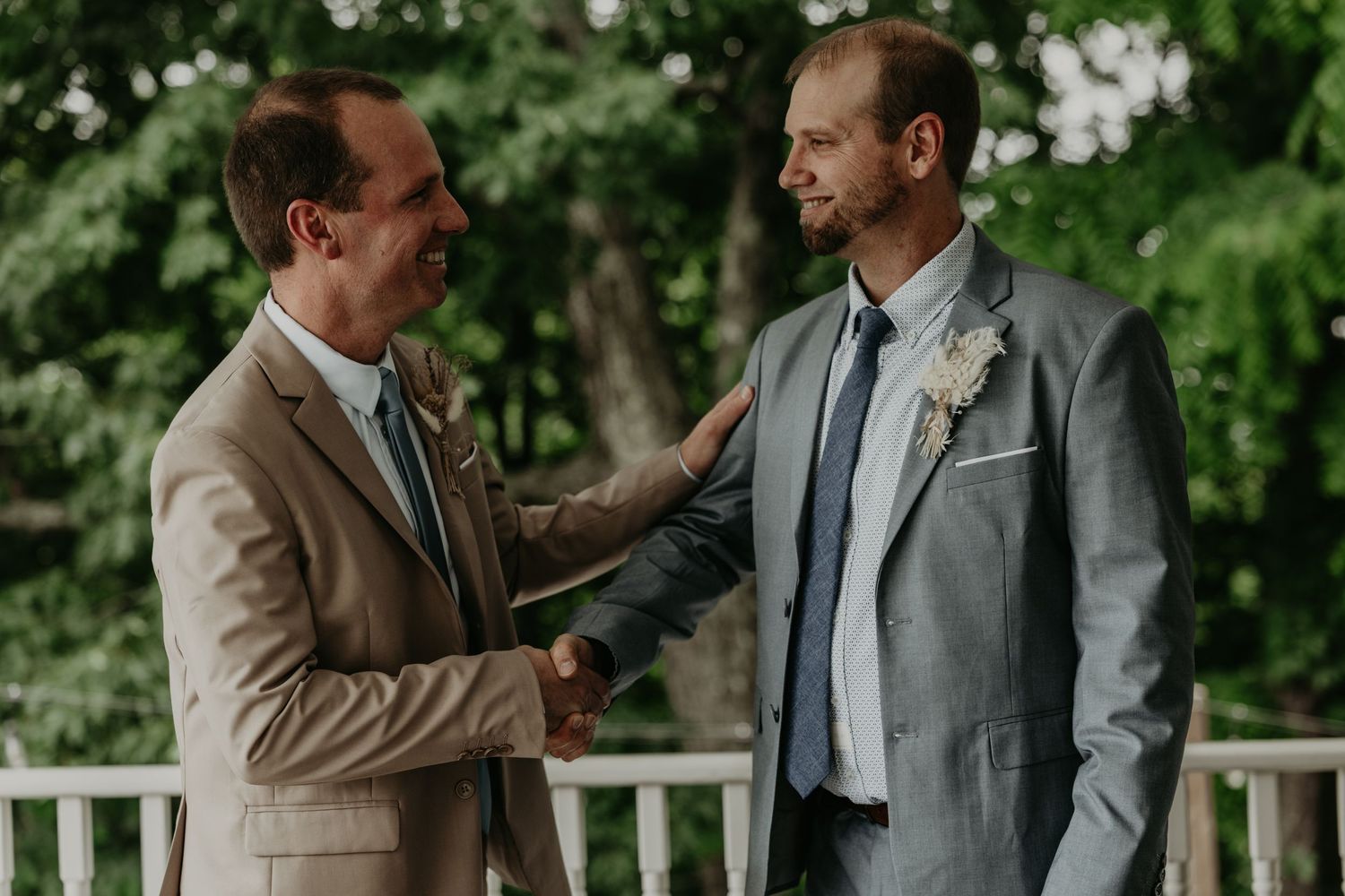 Two people in formal attire having an emotional conversation outdoors in a natural setting.