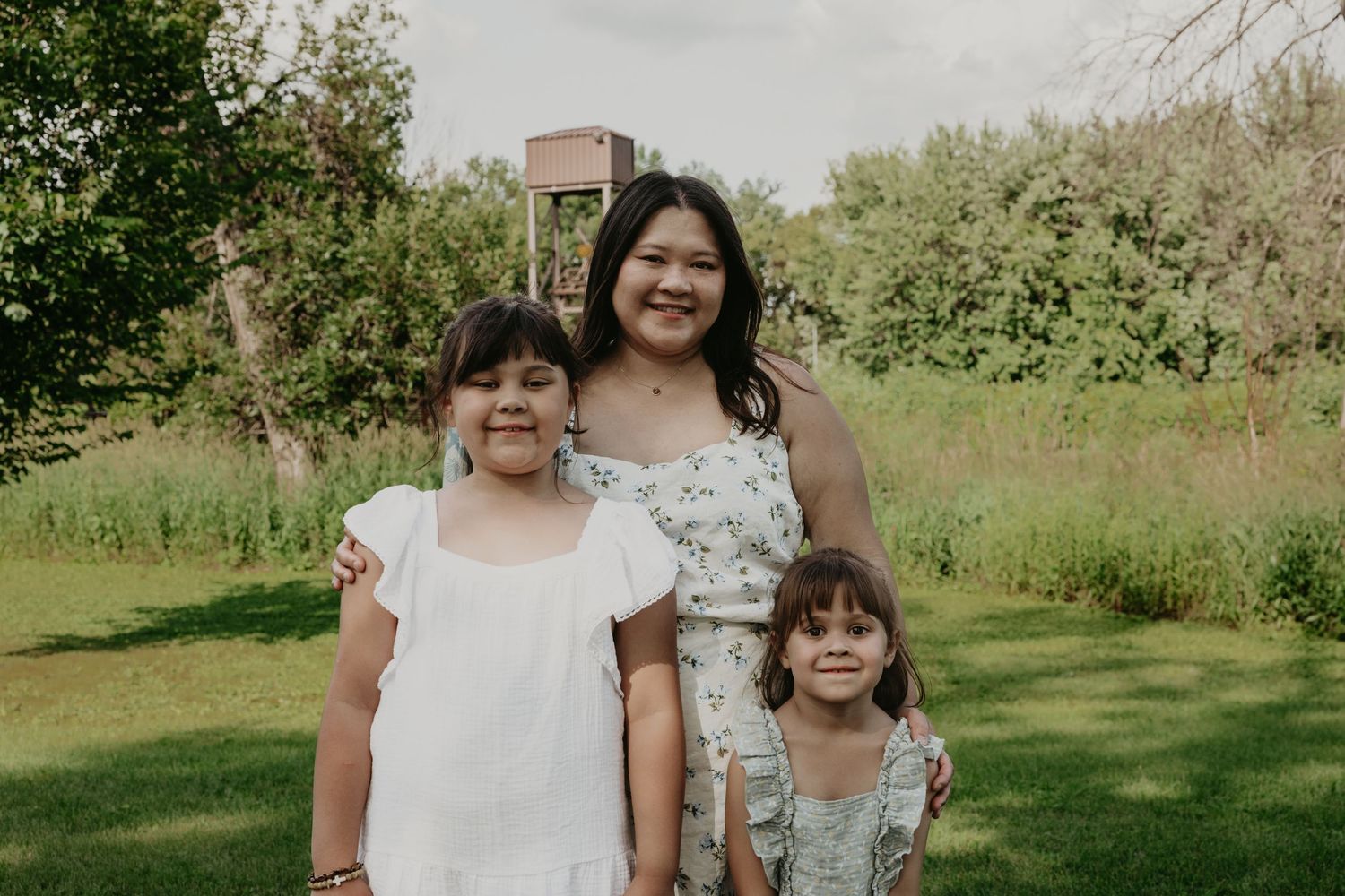 Candid family portraits taken in a natural outdoor setting with greenery.