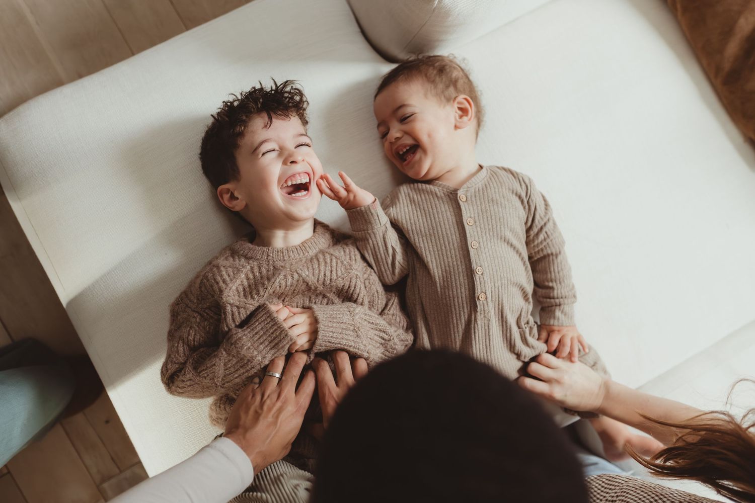 Family relaxing together in bed on a cozy morning while tickling the eldest child.