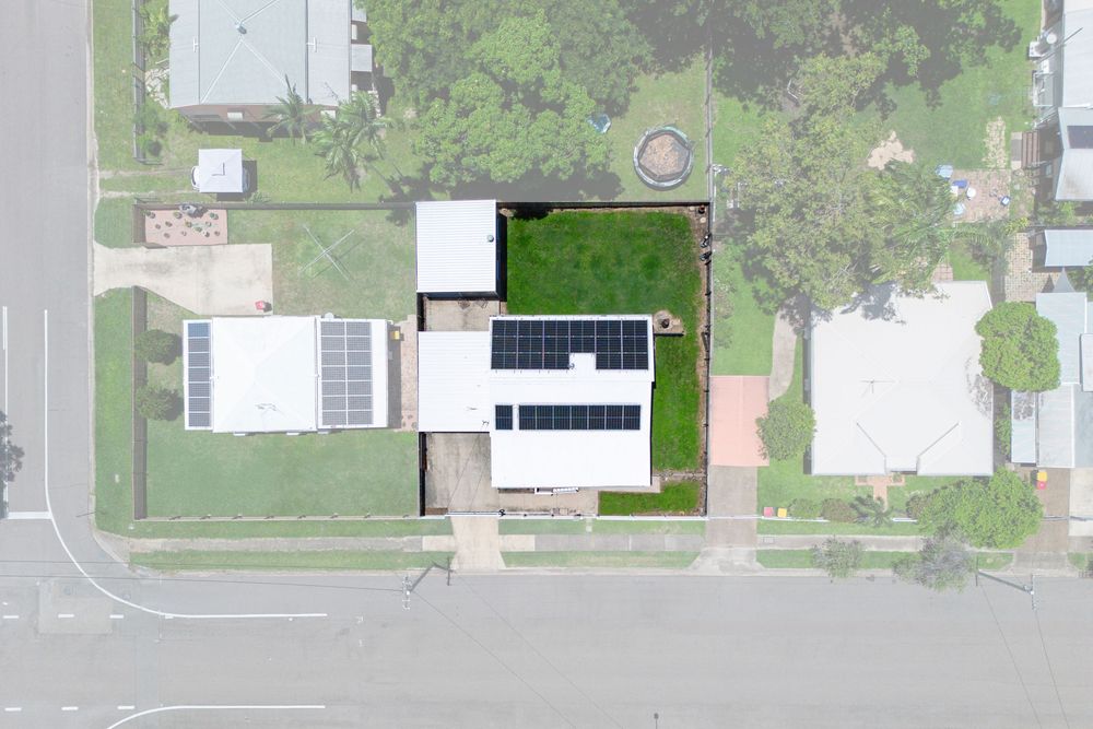 Aerial view of residential neighborhood with houses and streets surrounded by green trees and vegetation.