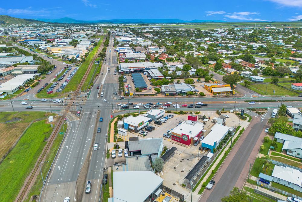 Aerial panoramic view of a coastal town with commercial buildings and roads stretching along the shoreline.