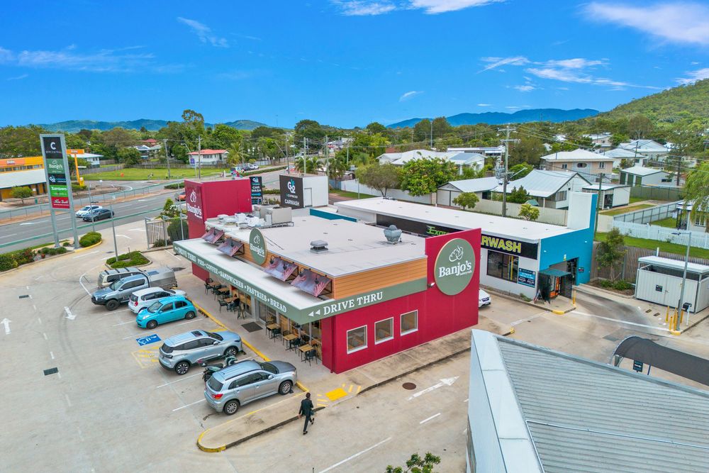 Aerial drone view of a small coastal town with colorful buildings and parked vehicles near the beach.