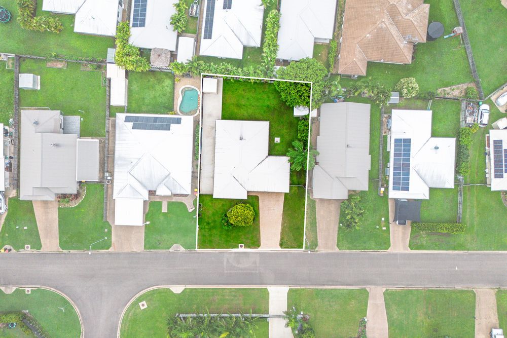 Aerial view of suburban neighborhood with green lawns and white houses arranged in neat rows.