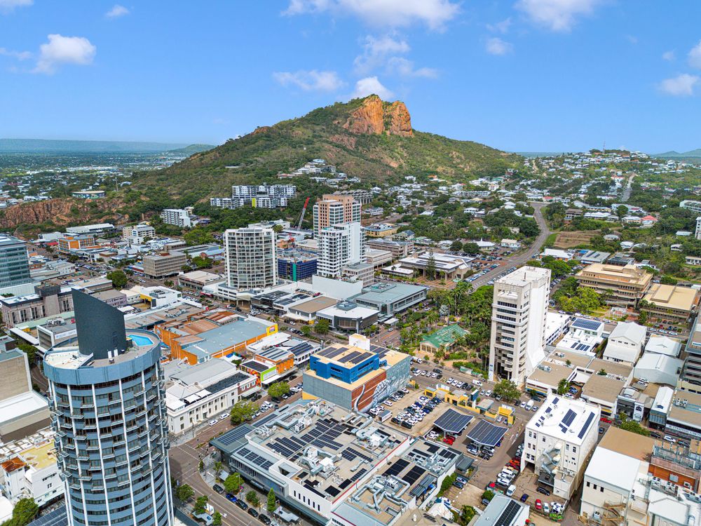 Aerial panoramic view of Port Louis cityscape with mountains and modern buildings under blue sky in Mauritius.