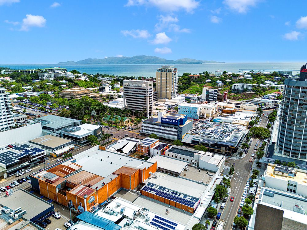 Aerial panoramic view of a coastal city skyline with modern buildings, beaches, and blue ocean waters.