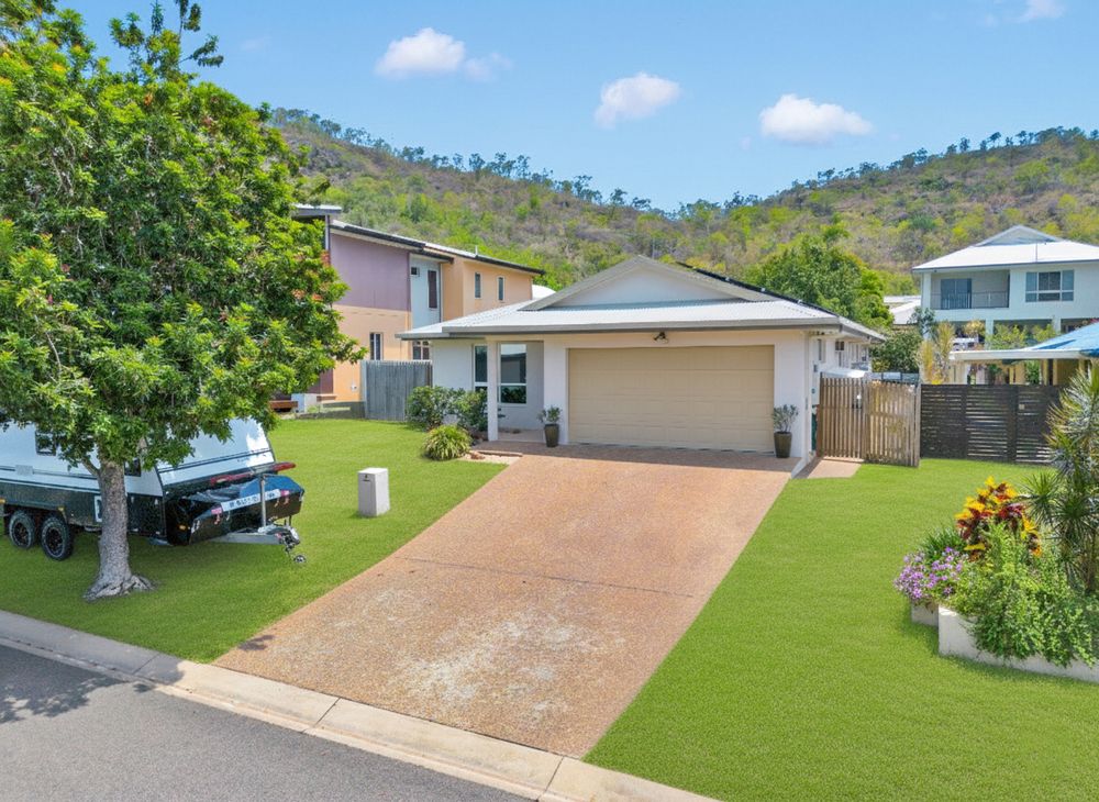 A steep residential driveway with green lawns and houses visible on a sunny day with blue skies and white clouds.