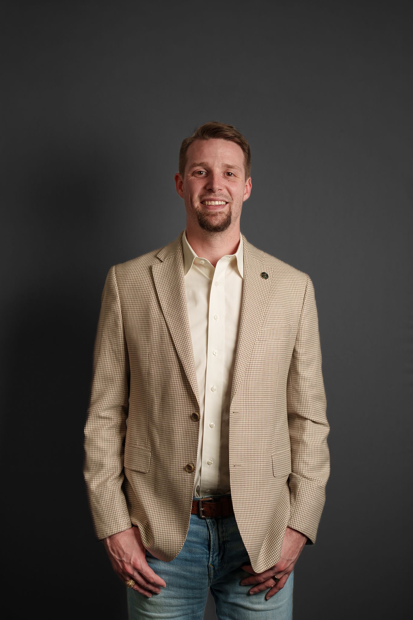 Professional portrait of someone in business attire with blue striped shirt and patterned tie.