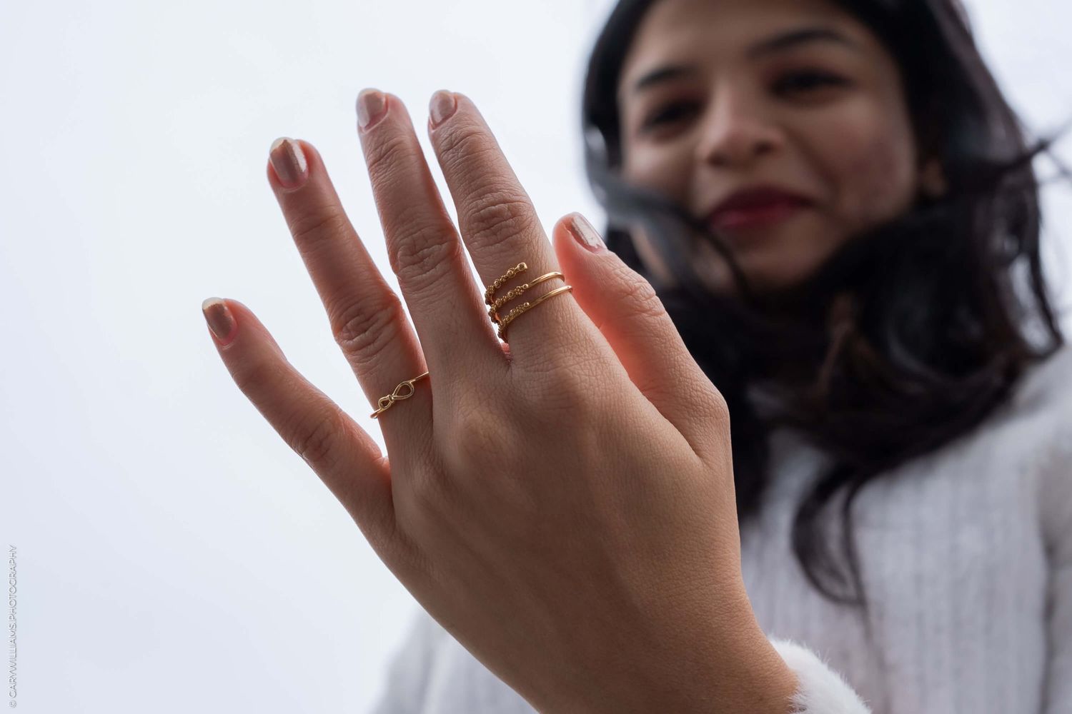 Close-up of a hand displaying engagement rings against a bright background.