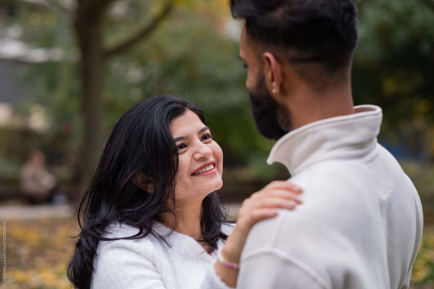 A romantic autumn moment shared in a park with falling leaves.