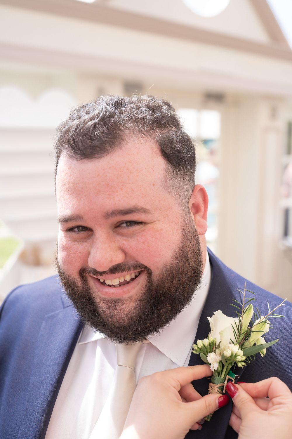 A joyful wedding guest wearing a blue suit with a white boutonniere.