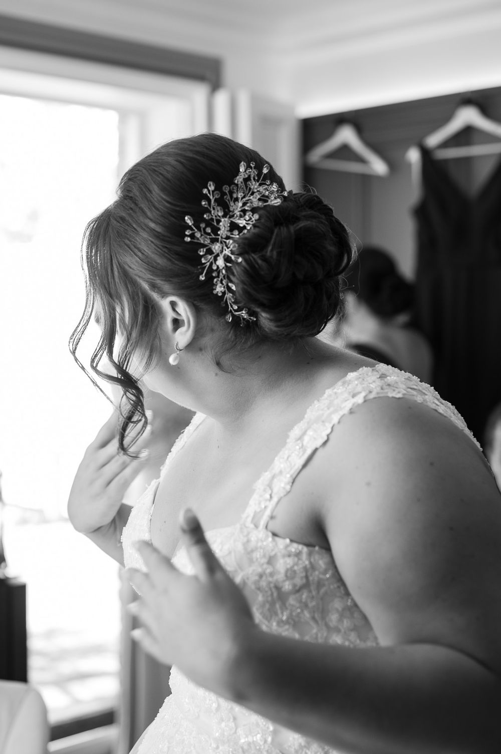Close-up of an elegant bridal hairstyle with crystal hair accessory and lace dress strap.