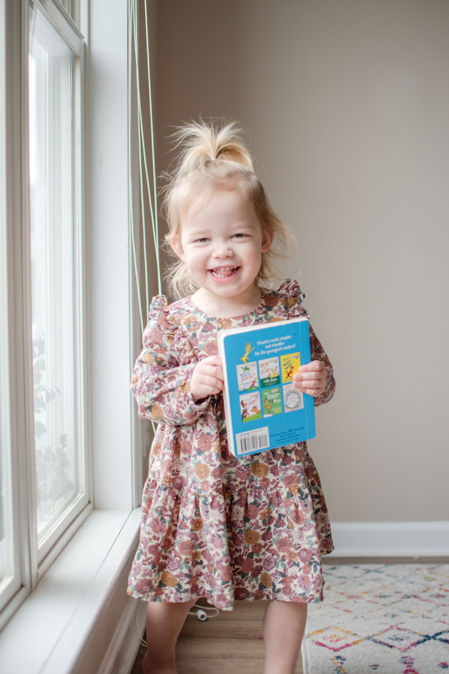 Little girl carries a book with her during a maternity photo shoot.