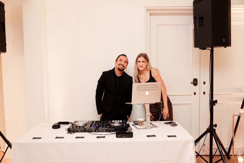 A DJ setup with equipment at a white decorated wedding venue.