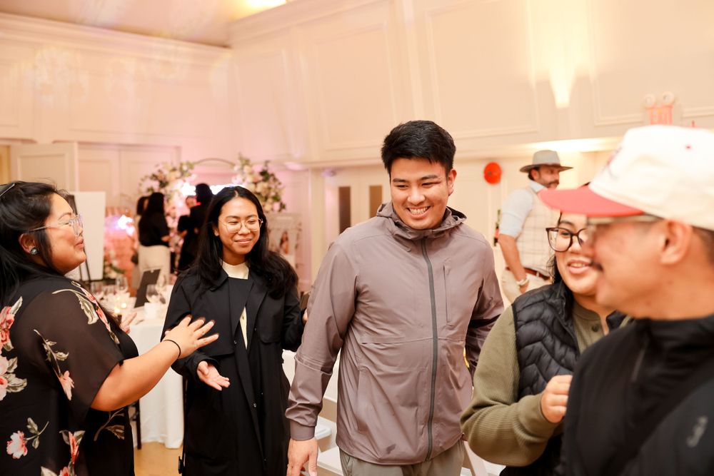 Lively group conversation at an indoor event with floral decorations in the background.