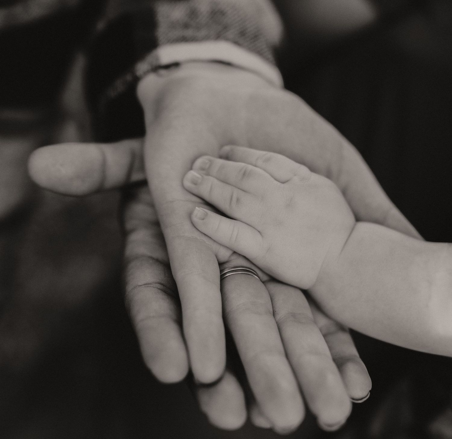 Artistic black and white close-up of hands reaching towards each other.