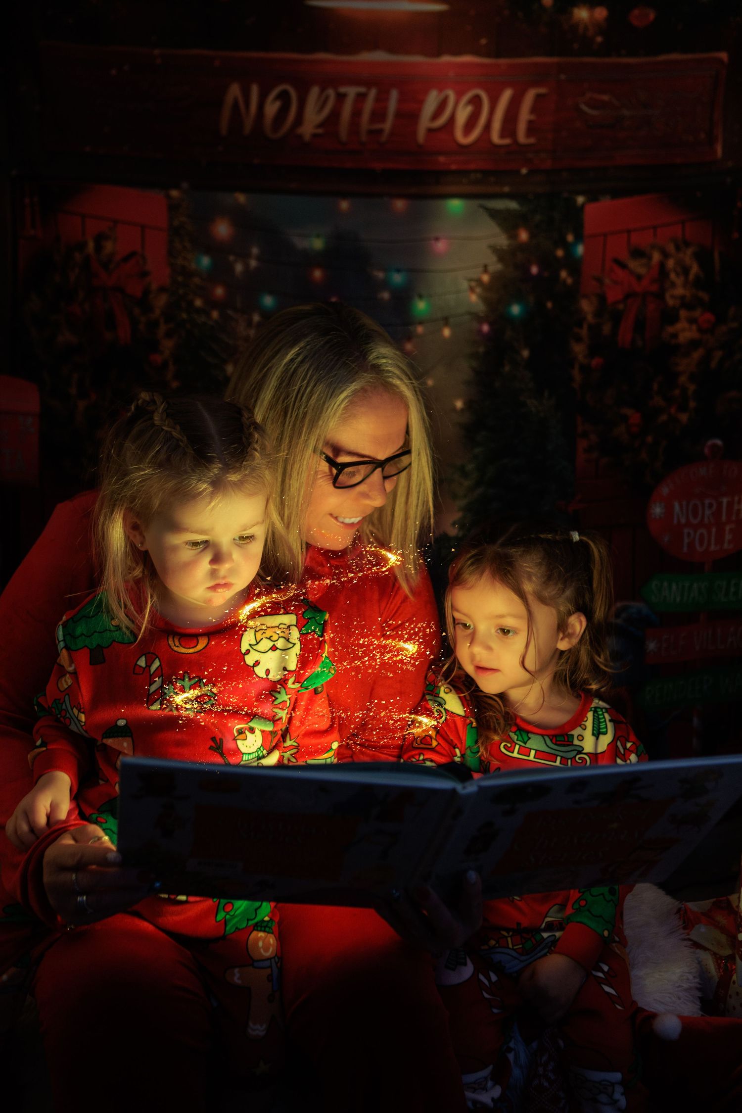 Children gather around a glowing red display creating a magical Christmas atmosphere in the dark.