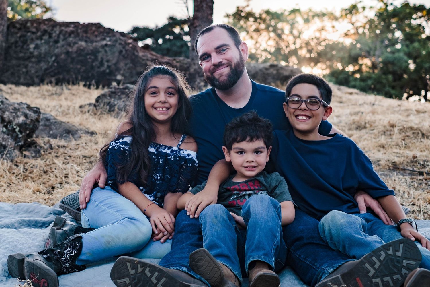 A family sits together in their front yard in valley springs california during golden hour sunset.
