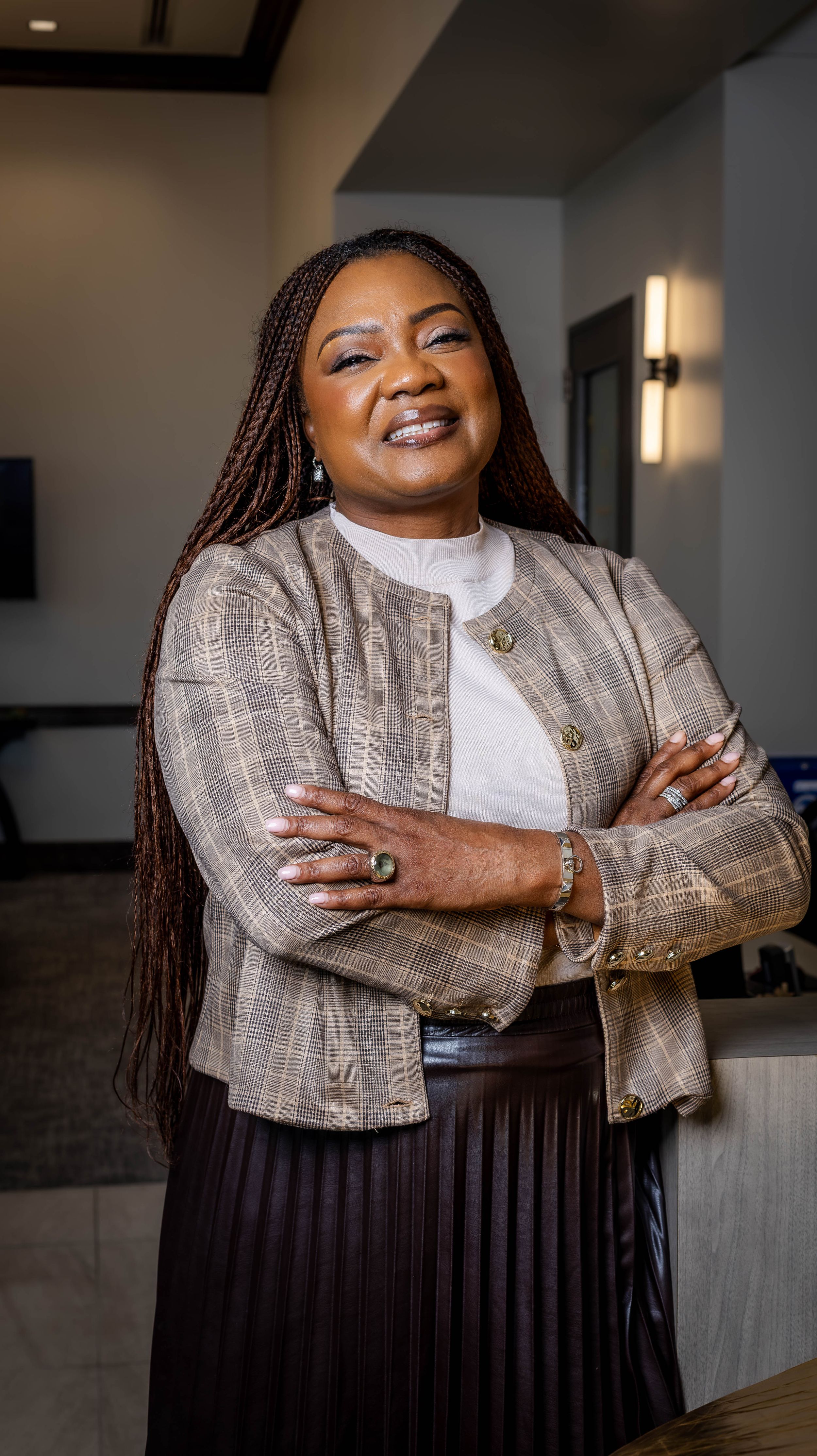 Professional portrait in modern office wearing plaid jacket and white turtleneck.
