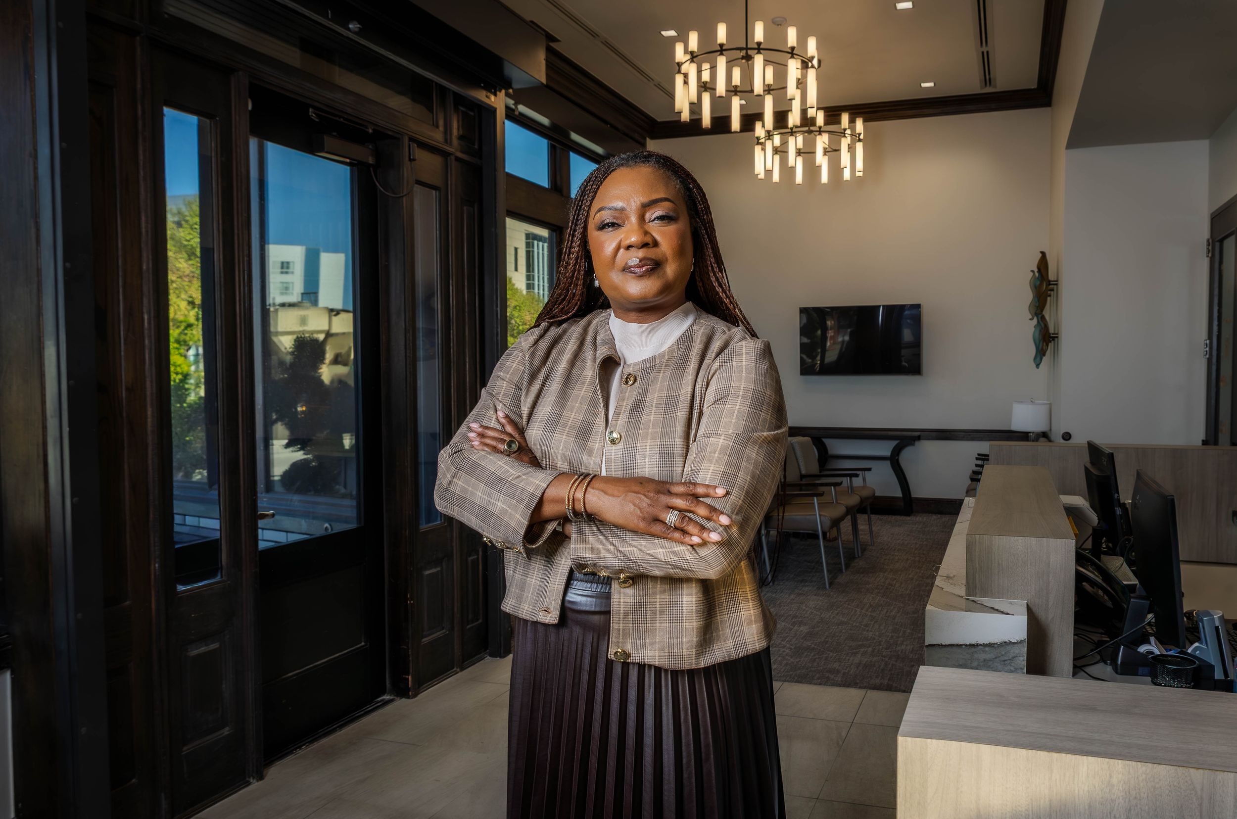 Professional business portrait in modern office space with chandelier lighting.