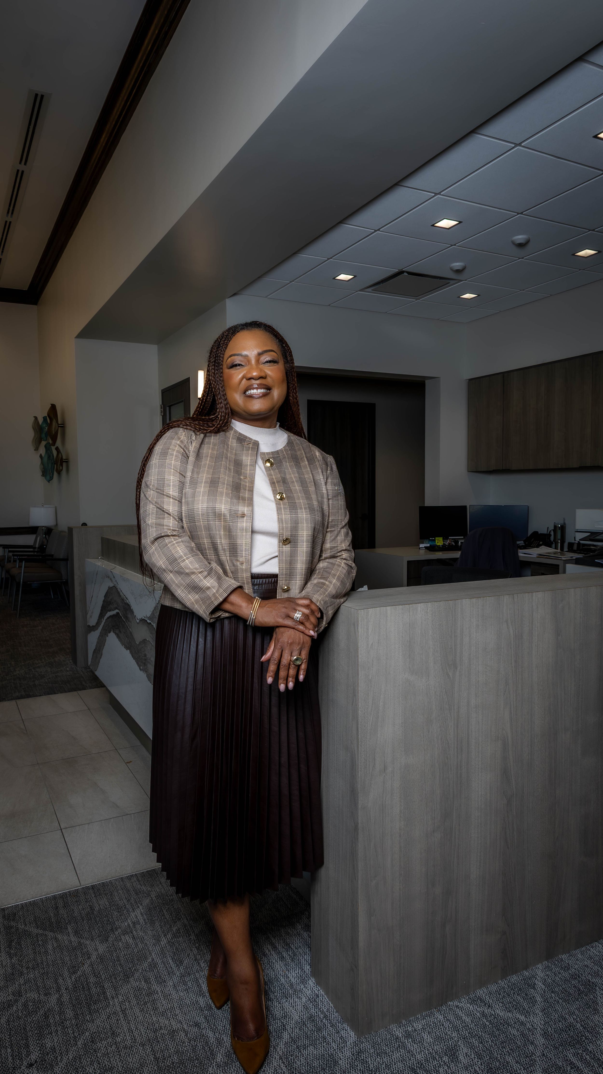 Professional full-length portrait in modern office setting with gray interior.
