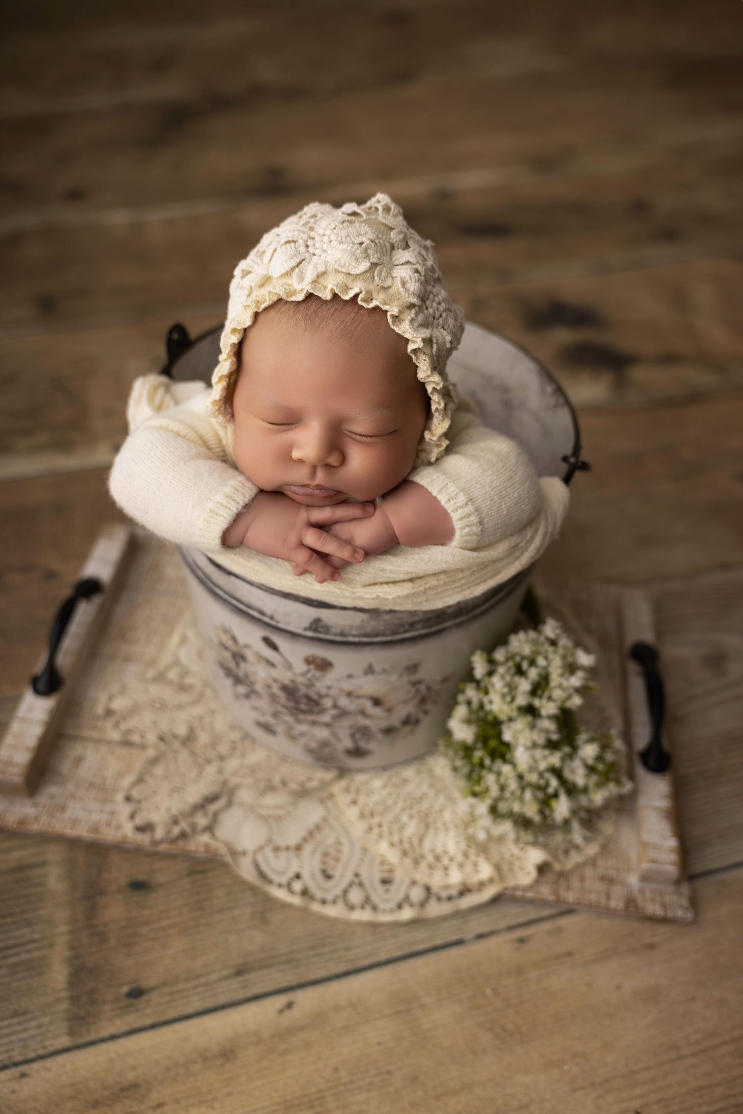 Baby in a red and white striped outfit placed in a bucket with red stuffing surrounded by winter greens
