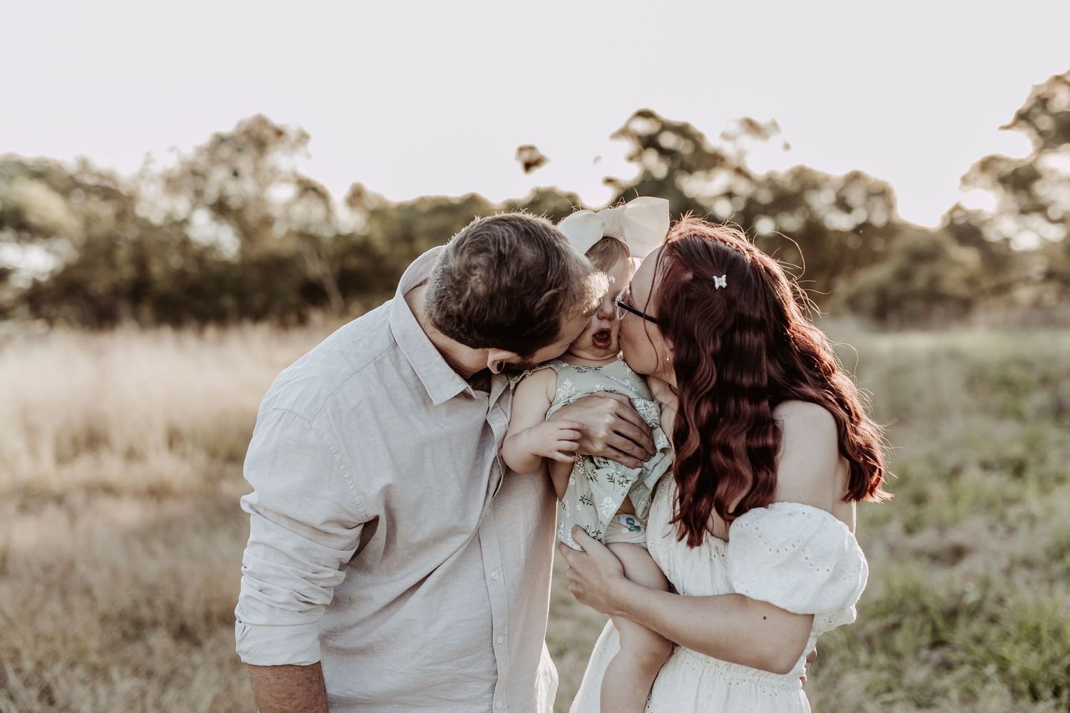 Candid family moment captured in golden sunlight amidst natural outdoor setting.