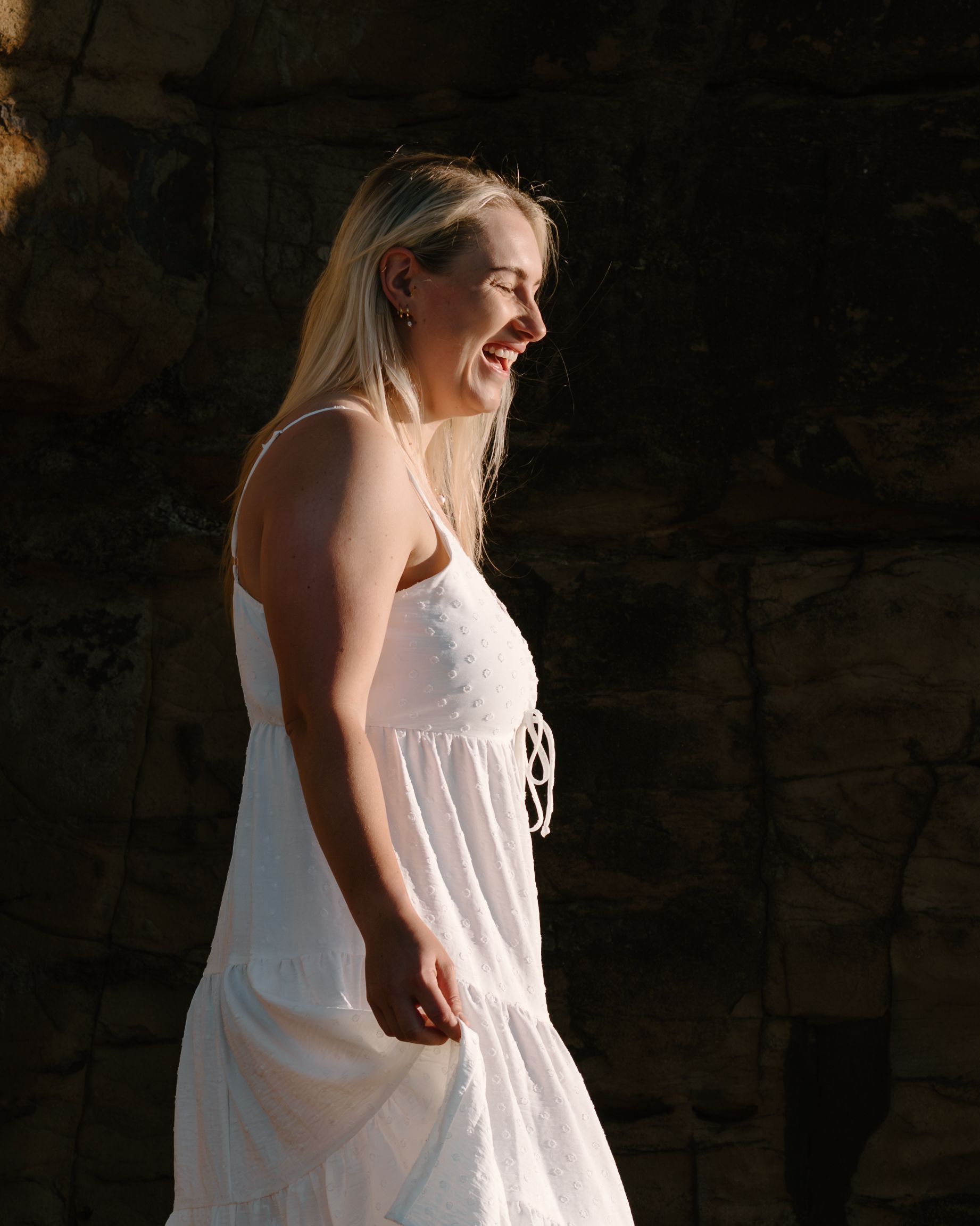 A figure in a flowing white dress stands dramatically in shadow against a dark background.