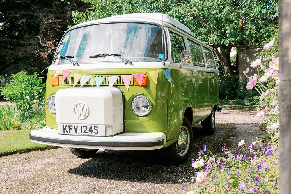 Classic vintage cars parked in a row outdoors with greenery and flowers in the background.