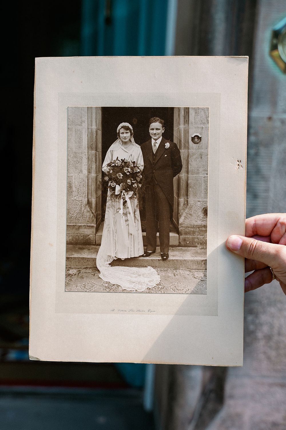 Hands holding an old black and white wedding photograph in a vintage setting.
