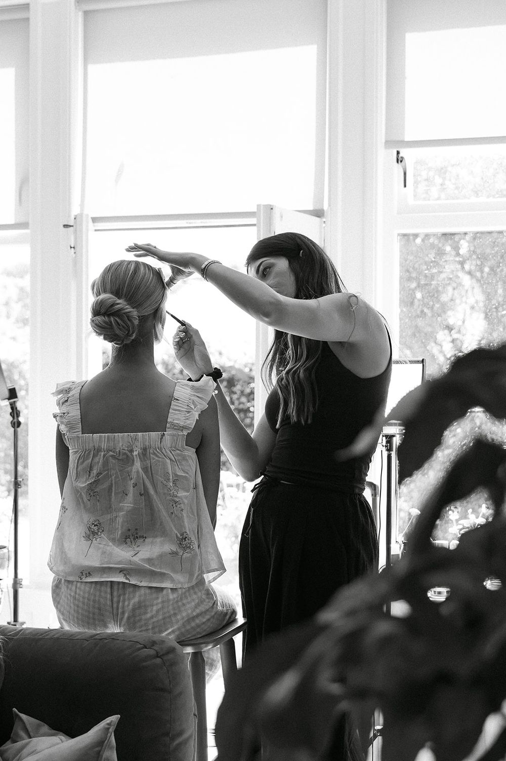Silhouettes of people getting ready in a bright sunlit room with large windows.
