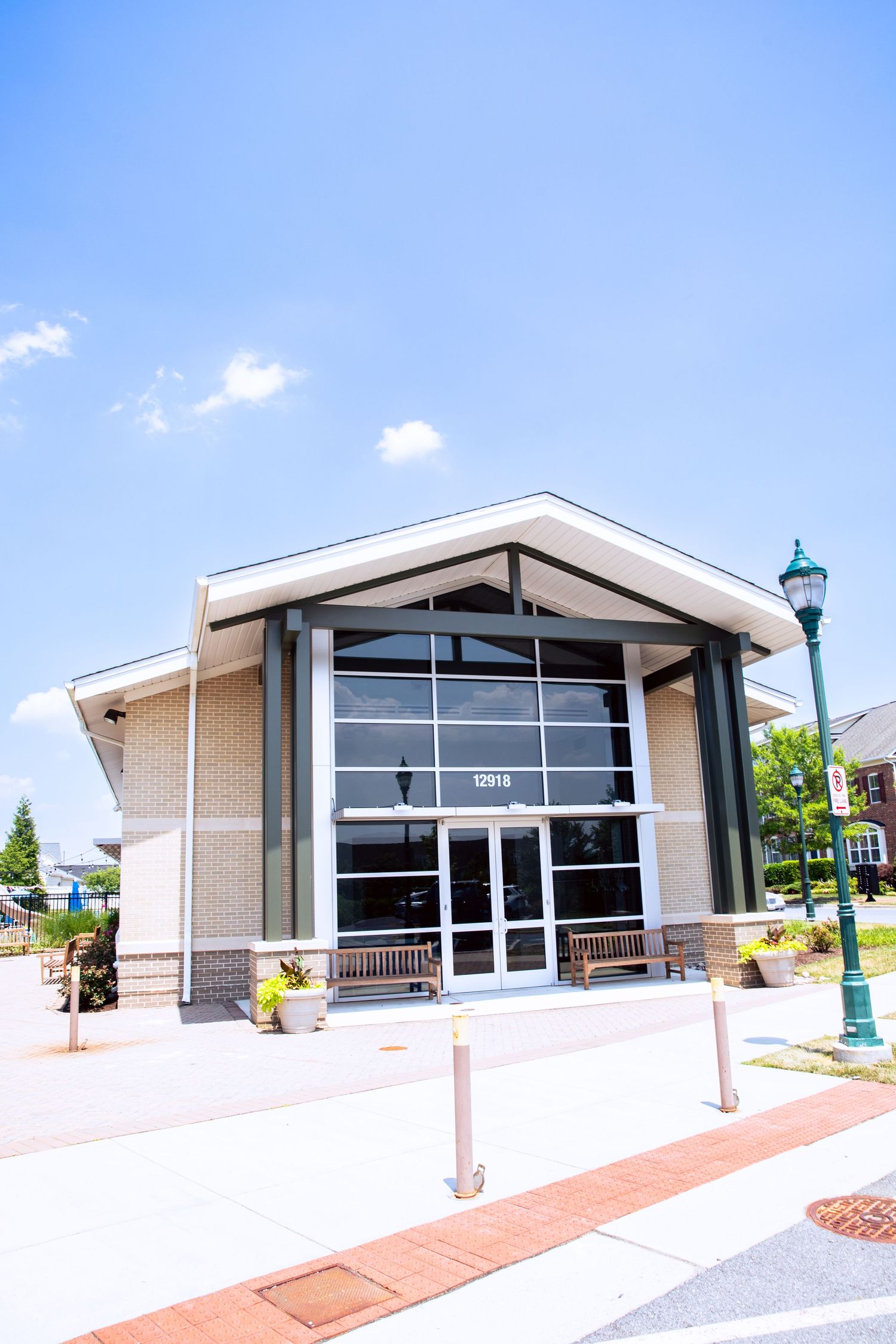 Modern church building exterior with angled roof and glass entrance doors on a sunny day with blue skies.