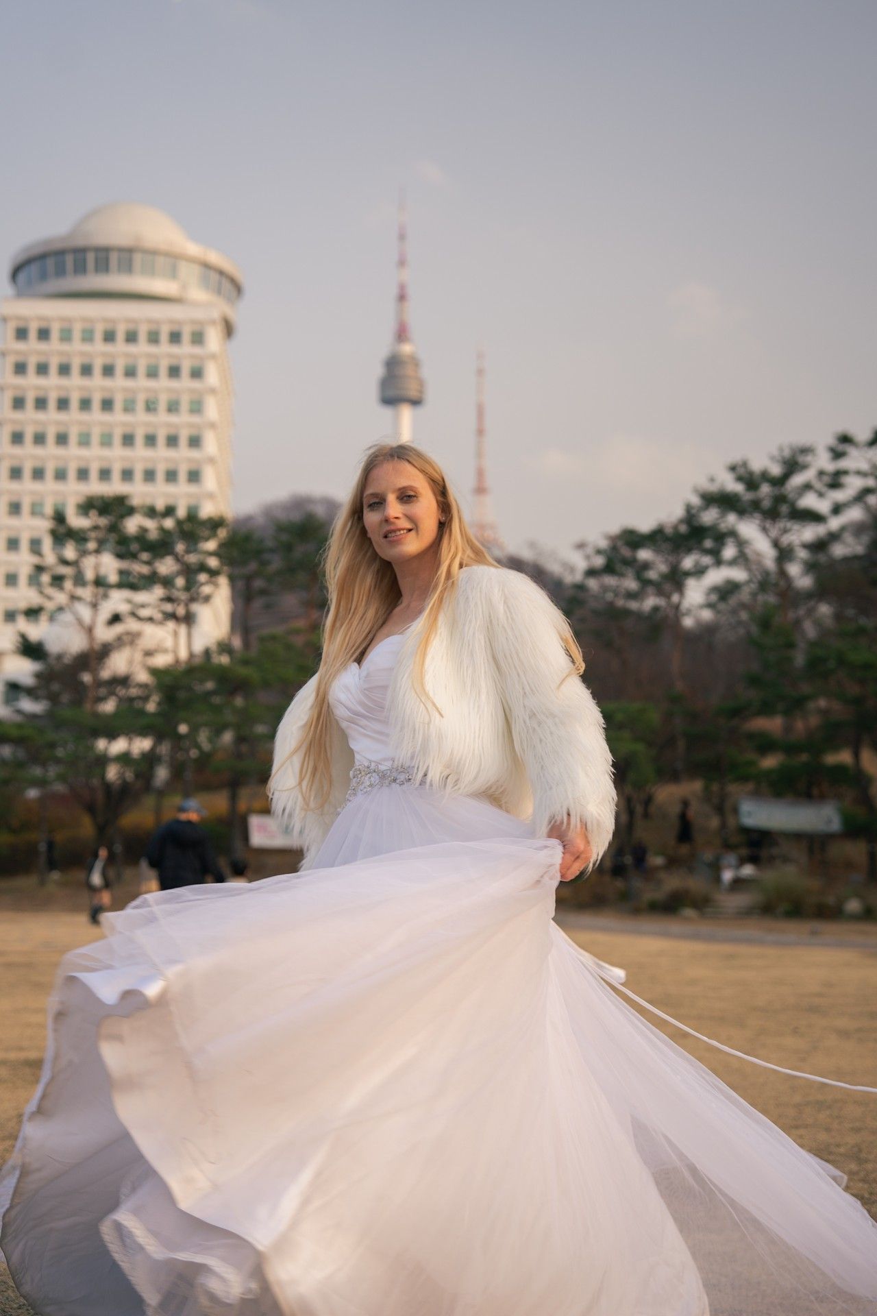 A person in a flowing white dress twirls gracefully in a series of outdoor photos with city buildings in the background.