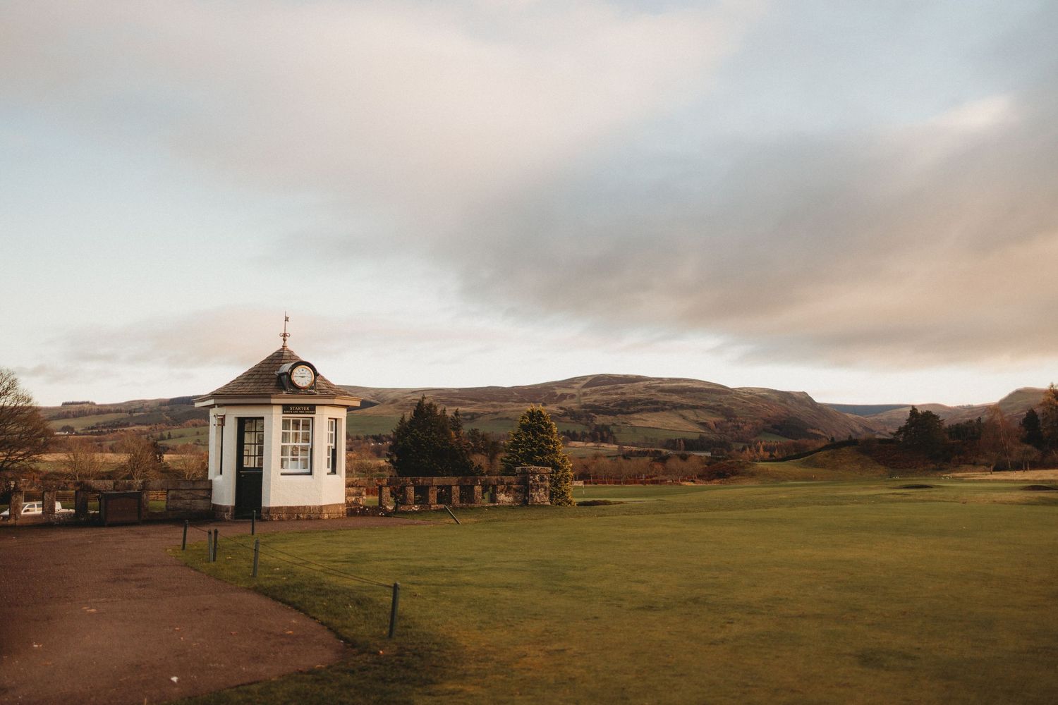 A panoramic view of rolling green hills and rural countryside with scattered buildings under cloudy skies. gleneagles Hotel Golf Course
