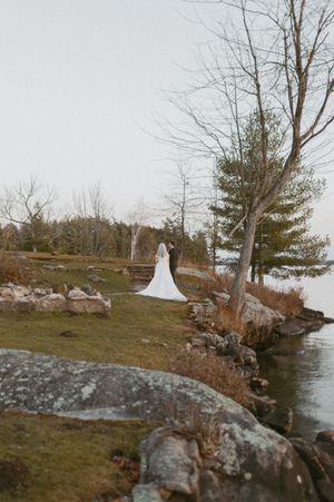 Rocky shoreline landscape with bare trees and a bride in white visible in the distance.
