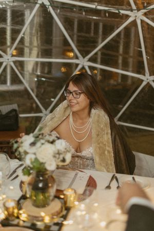 An elegant wedding reception table setting with white floral centerpieces and candlelight.