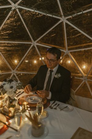 Wedding reception table setting in a geodesic dome with ambient lighting and elegant place settings.