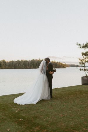 A couple shares an intimate moment by the waterfront during their wedding photoshoot.