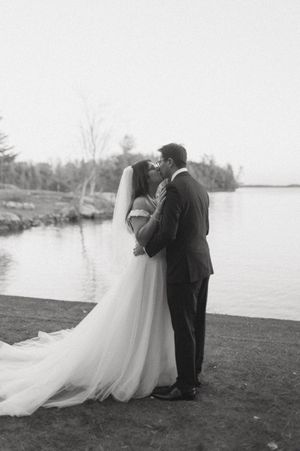 Black and white wedding photos capture intimate moments between newlyweds by the water.