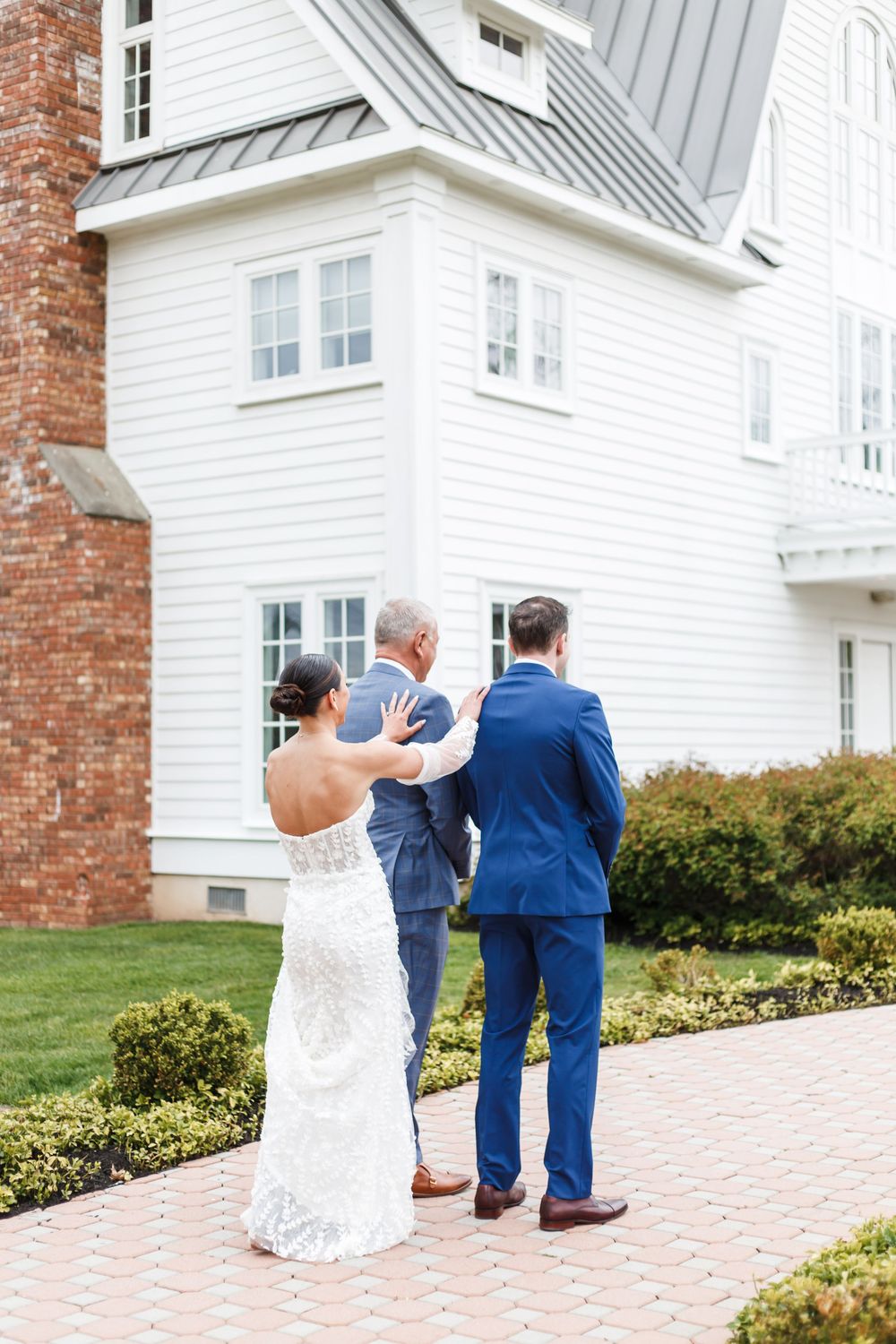 Couple walking together on a brick pathway outside a white colonial-style building.
