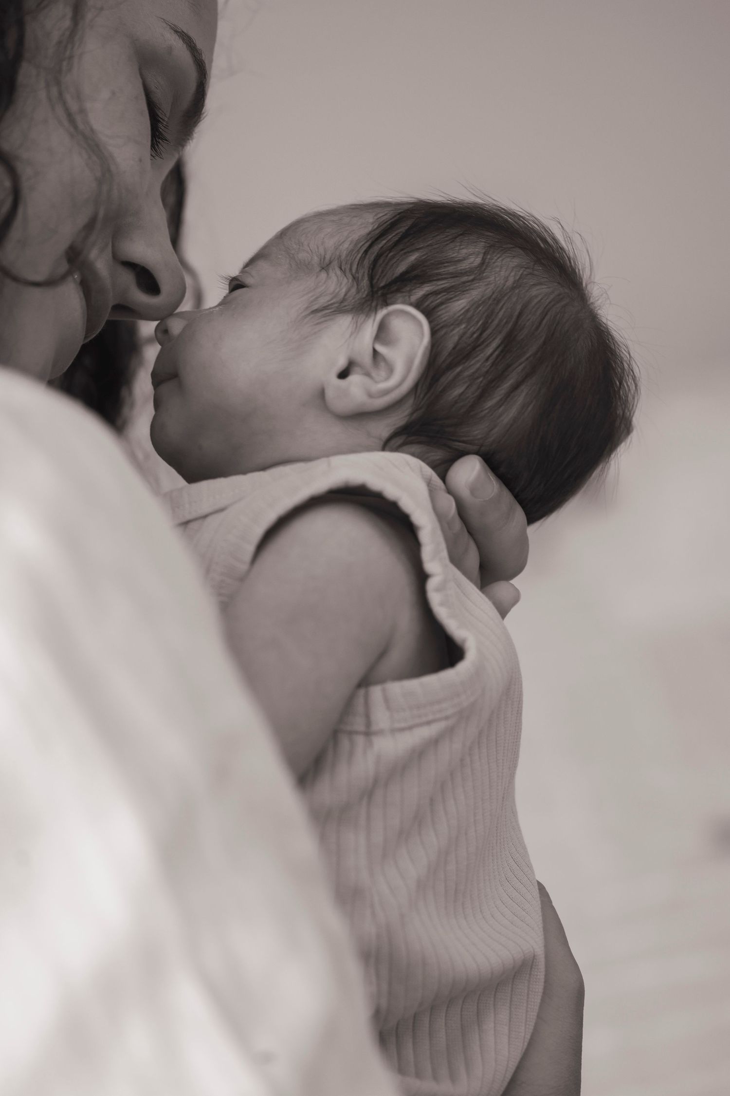 Close-up black and white portrait of newborn being cradled.