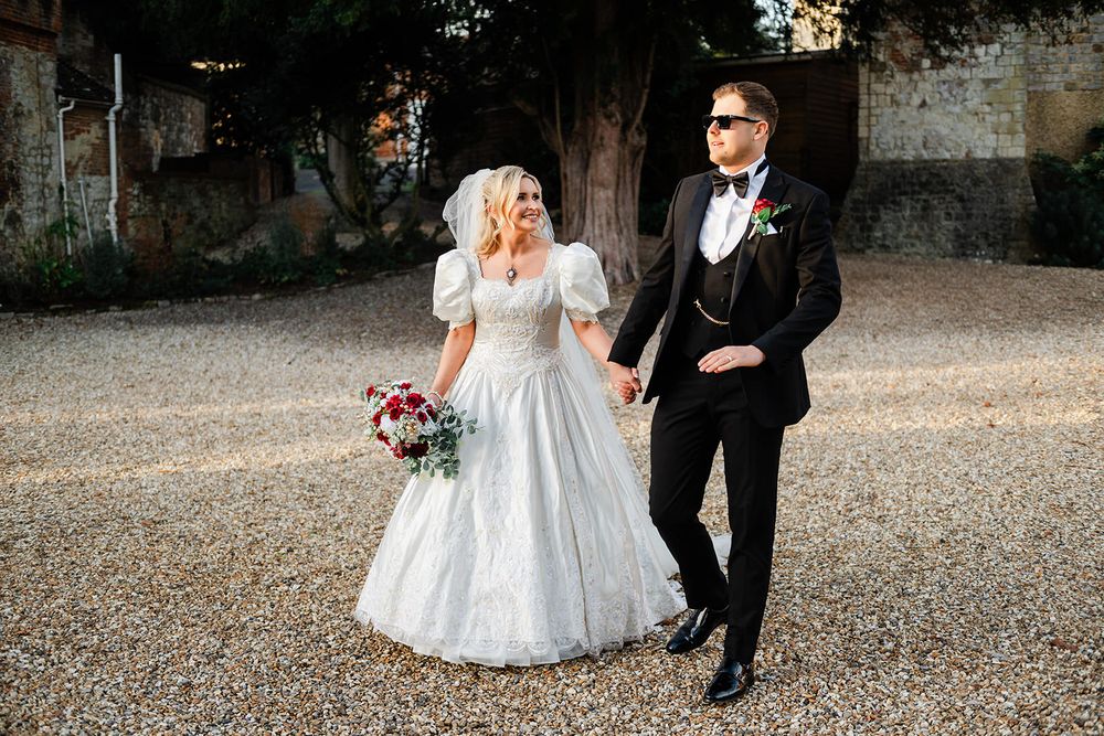 A bride and groom walk together on a gravel path during an outdoor autumn wedding ceremony.