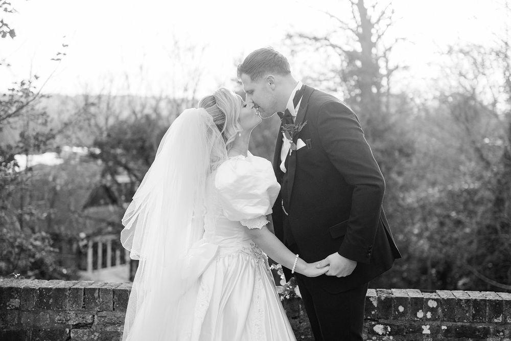 A black and white wedding photo series showing romantic moments between a couple in an outdoor garden setting.
