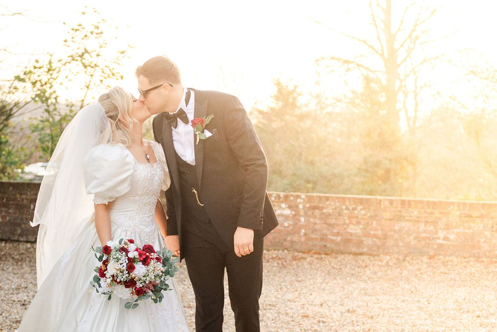 A couple shares a romantic moment at sunset in an outdoor garden setting with warm golden light.