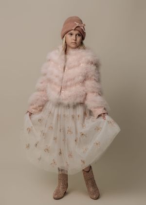 Child wearing pink fluffy coat and tulle dress with sparkly boots in studio photography sequence.