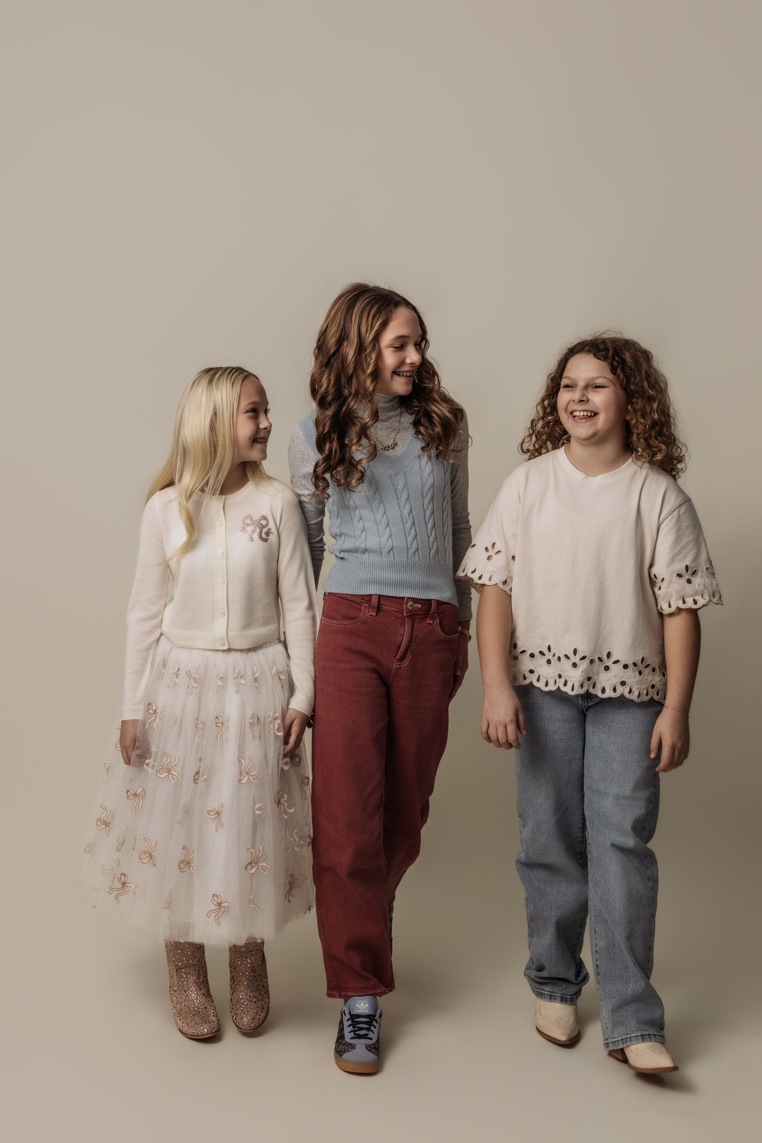 Children in coordinated casual outfits pose against neutral studio background.