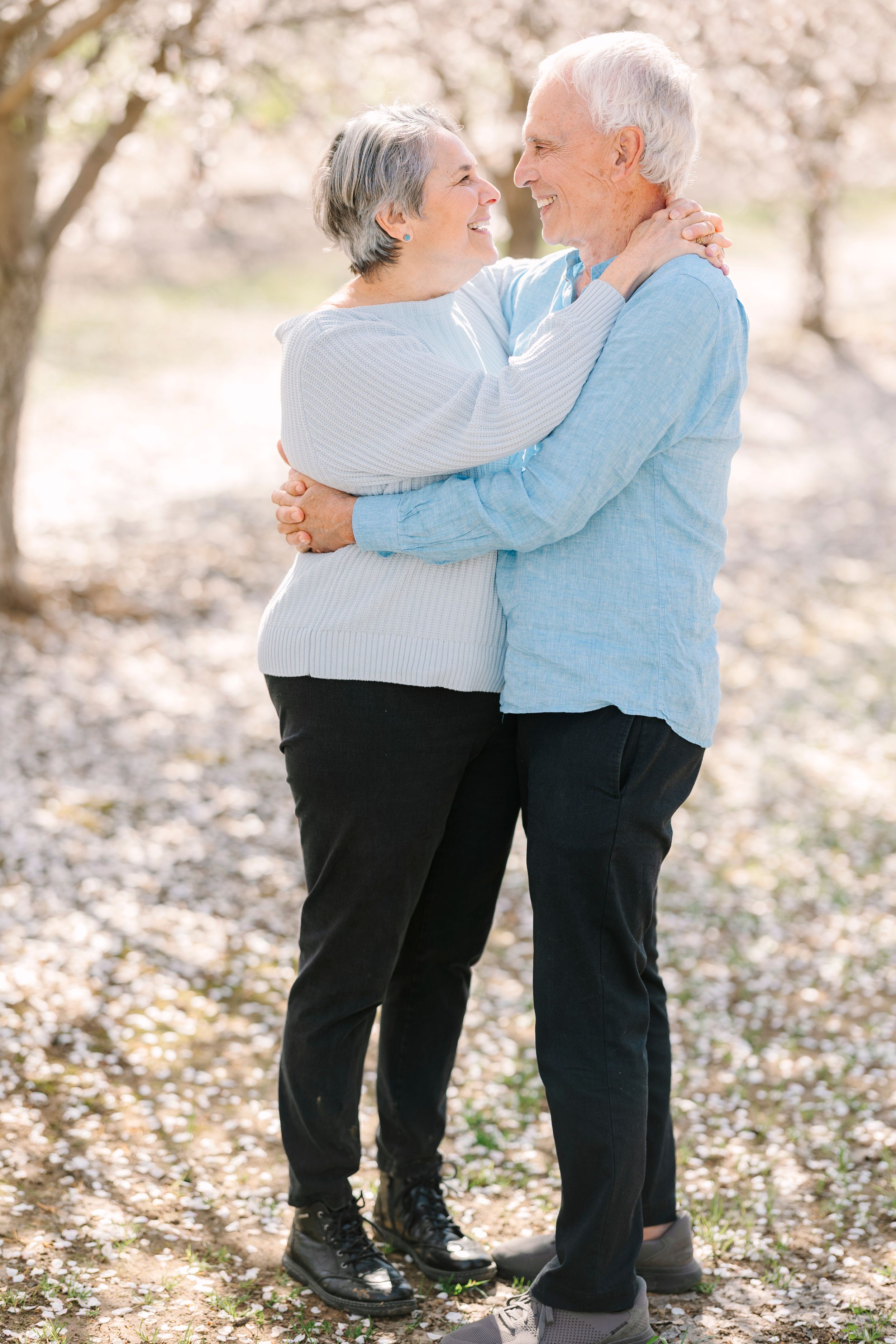 Senior couple sharing tender moments while standing together on fallen leaves.