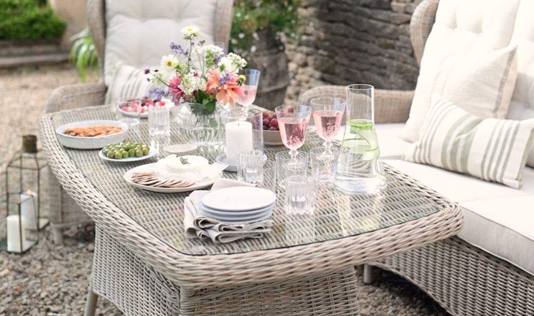 Outdoor patio furniture with cushions and table settings arranged for entertaining.