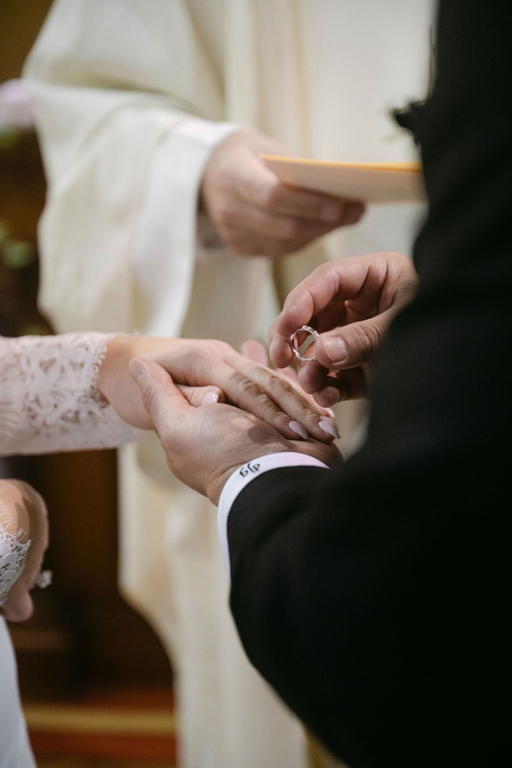 Close-up sequence of hands exchanging wedding rings during a traditional ceremony.