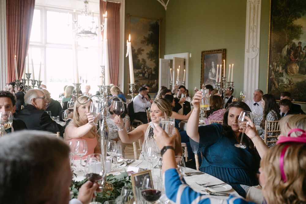 An elegant dining room setup with crystal chandeliers and tables decorated for a formal celebration.